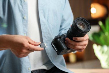 Bir adam fotoğraf makinesine SD bellek kartı yerleştiriyor.