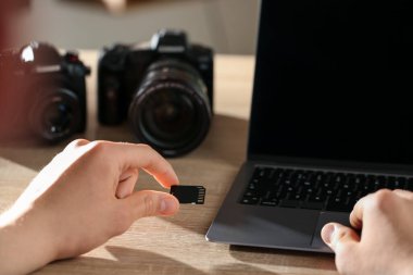 SD bellek kartını bilgisayarın içine yerleştiren adam ahşap masa, yakın plan