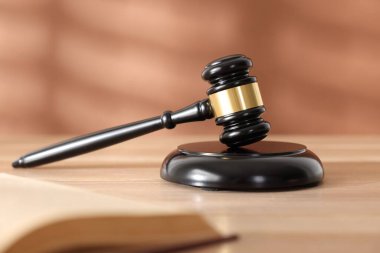 Hakimin tokmağı, ses bloğu ve tahta masa üzerindeki kitap mercan arka planına karşı, seçici odaklanma