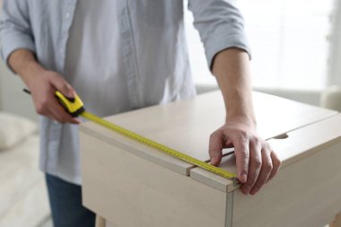 İçerideki bantla ahşap dolabı ölçen adam, yakın plan.