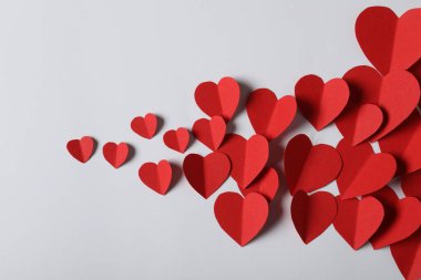 Açık gri arkaplanda bir sürü kağıt kalp var.