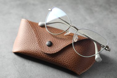 Gri masada şık gözlükleri olan bir çanta, yakın plan.