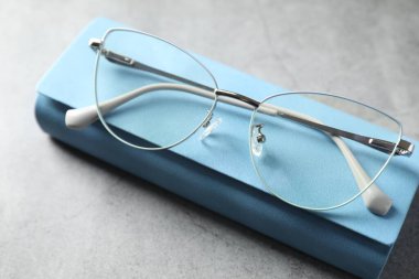 Gri masada şık gözlükleri olan bir çanta, yakın plan.