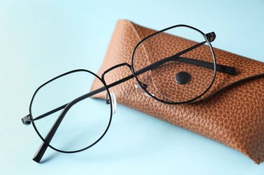 Açık mavi arka planda şık gözlüklü çanta, yakın plan