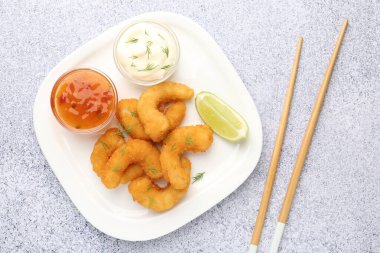 Lezzetli tempura karidesleri, kireç, sos ve çubuklar gri desenli masa, düz yatış.