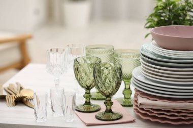 Temiz bardaklar, tabaklar, çatal bıçak takımı ve yeşil saksı.