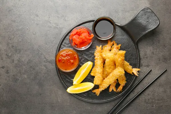 Limon, zencefil ve sosla servis edilen lezzetli tempura karidesleri gri desenli masa, düz yatak. Metin için boşluk