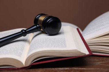 Hakimin tokmağı ve kitapları ahşap masada, kahverengi arka planda, yakın plan.