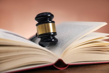 Hakimin tokmağı ve açık kitabı soluk kahverengi arka plana karşı, yakın plan.