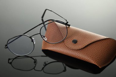 Gri ayna yüzeyinde şık gözlükler ve çanta, yakın plan.