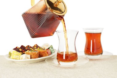 Masadaki cam fincana sıcak Türk çayı dökülüyor, beyaz arka plan, yakın plan