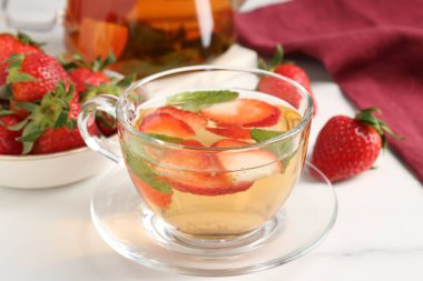 Çilekli aromalı meyve çayı ve beyaz mermer masada nane şekeri, yakın plan.