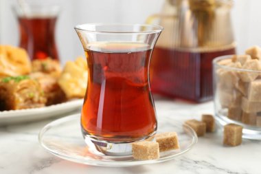 Lezzetli Türk çayı, beyaz mermer masada şekerlerle servis edilir, yakın plan.