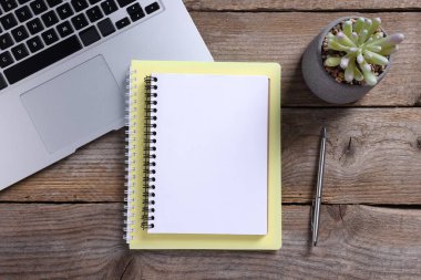 Boş defterler, dizüstü bilgisayarlar, ev bitkisi ve kalem ahşap masa, düz uzanma