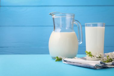 Taze süt ve çiçekler açık mavi masada, yakın plan. Metin için boşluk