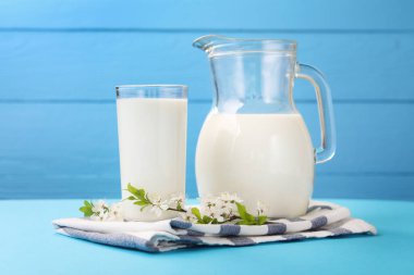 Açık mavi masada taze süt ve çiçekler, yakın plan.