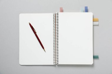 Açık gri arkaplanda renkli çıkartmalar ve kalemle boş bir defter aç, üst görünüm