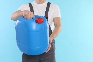 Açık mavi arka planda plastik kutu tutan adam, yakın plan. Metin için boşluk