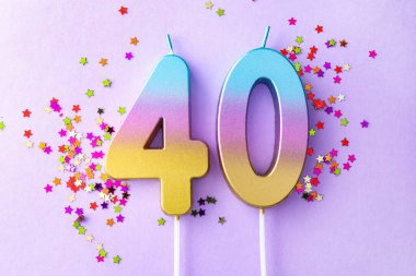 40th birthday. Number shaped candles and confetti on violet background, flat lay