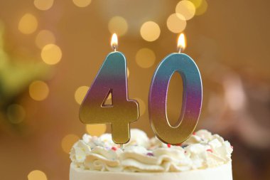 40. yaş günü. Pastanın üzerinde yanan mumlar arka planda bulanıklık yaratıyor. Işıklar, yakın plan. Bokeh etkisi