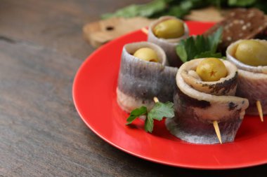 Ahşap masada zeytinli ve maydanozlu lezzetli ringa dürümleri, yakın plan. Metin için boşluk