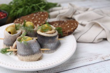 Zeytinli lezzetli ringa dürümleri, beyaz ahşap masada dereotu ve ekmek, yakın plan. Metin için boşluk