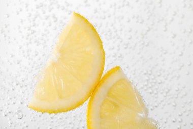 Arka planda limon dilimleri olan soda, yakın plan.