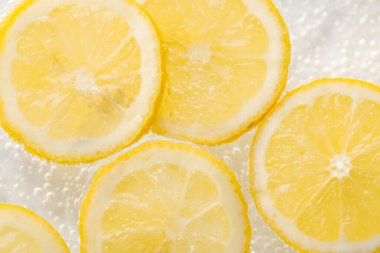 Arka planda limon dilimleri olan soda, yakın plan.