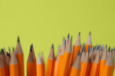 Yeşil arkaplanda birçok grafit kalem, yakın plan