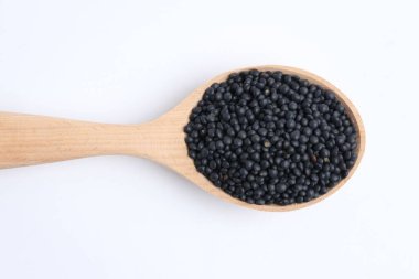 Raw lentils in wooden spoon isolated on white, top view