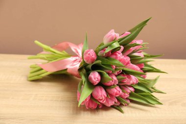 Tahta masadaki güzel laleler koyu bej arka planda, yakın planda.