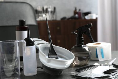 Kuaför salonundaki gri masada çamaşır suyu ve kuaför aletleri.