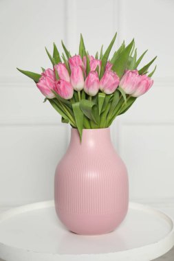 Beyaz masadaki vazoda duran bir buket güzel lale.