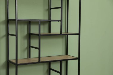 İçerideki zeytin duvarının yanındaki boş ahşap raf ünitesi.