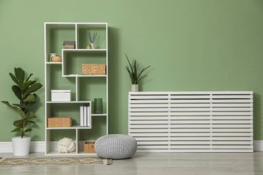 Salon içinde zeytin duvarının yanında farklı dekorasyonu olan ahşap raf ünitesi.