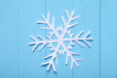Mavi ahşap zemin üzerinde bir kağıt kar tanesi, üst manzara.