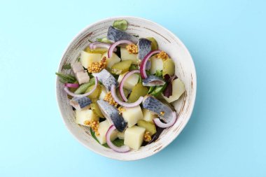 Ringa balıklı lezzetli salata, sebze ve açık mavi arka planda hardal, üst manzara.