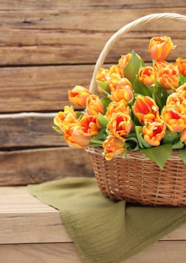 Hasır sepetteki güzel laleler ahşap masada.