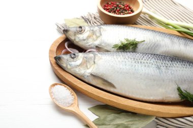 Tuzlu ringa balıkları ve baharatlar beyaz ahşap masada, yakın plan. Metin için boşluk