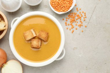 Açık gri masada kızarmış ekmeklerle servis edilen leziz mercimek kremalı çorba. Metin için boşluk