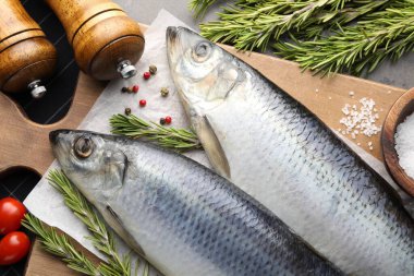 Tuzlu ringa balıkları, baharatlar ve domatesler gri masada, düz yerde.