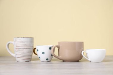 Açık ahşap masada bej arka planda bir sürü renkli fincan var. Metin için boşluk