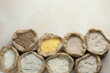 Beyaz masadaki kağıt torbalarda farklı türde un, düz yerde. Metin için boşluk
