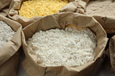 Beyaz masadaki kağıt torbalarda farklı türde un, yakın plan.