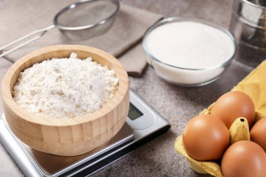 Mutfak terazisi, bir kase un ve gri desenli masa üzerindeki diğer ürünler, yakın plan.