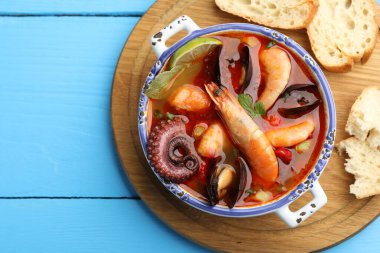 Lezzetli deniz ürünleri çorbası ve mavi ahşap masada bir parça ekmek.