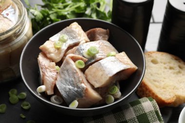 Siyah masada yeşil soğanlı lezzetli ringa balıkları, yakın plan.