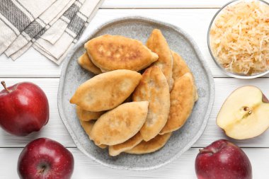 Lezzetli kızarmış pirizky (doldurulmuş turtalar) ve beyaz ahşap masa üzerinde elmalar, düz yatıyordu.