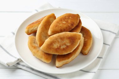 Lezzetli kızarmış pirizky (doldurulmuş turtalar) beyaz ahşap masada, yakın plan