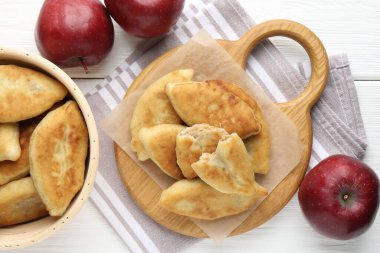 Lezzetli kızarmış pirizky (doldurulmuş turtalar) ve beyaz ahşap masa üzerinde elmalar, düz yatıyordu.